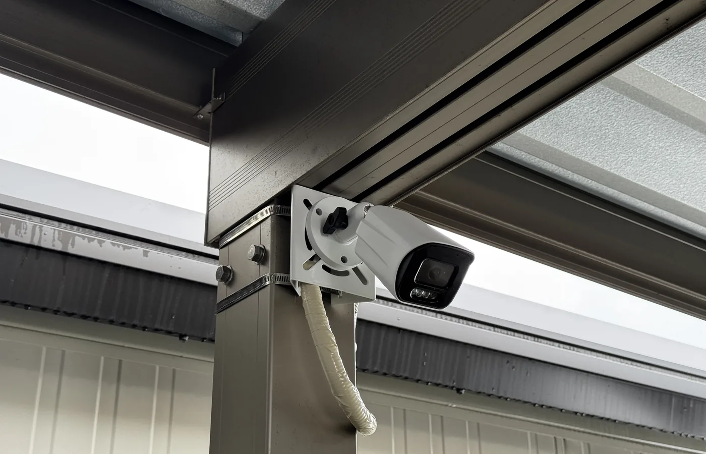 カーポートの柱に設置した屋外用バレット型防犯カメラと、PF管で保護された配線